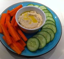 photo of ceramic plate with sliced vegetables and fresh hummus